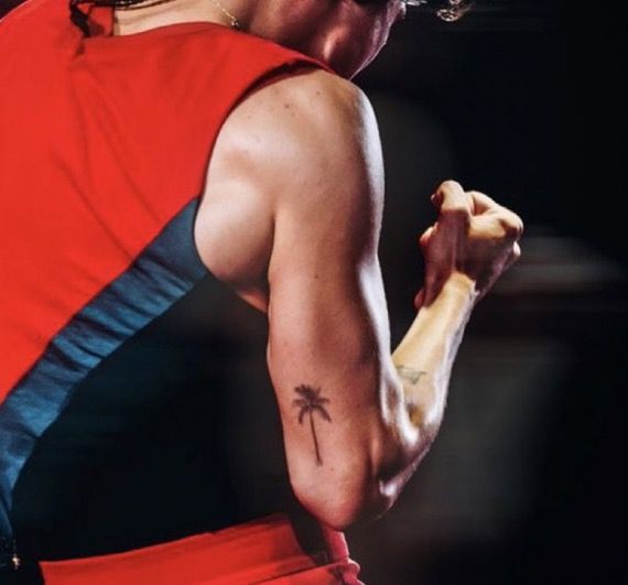 a man with a tattoo on his arm holding a baseball bat and wearing a red shirt