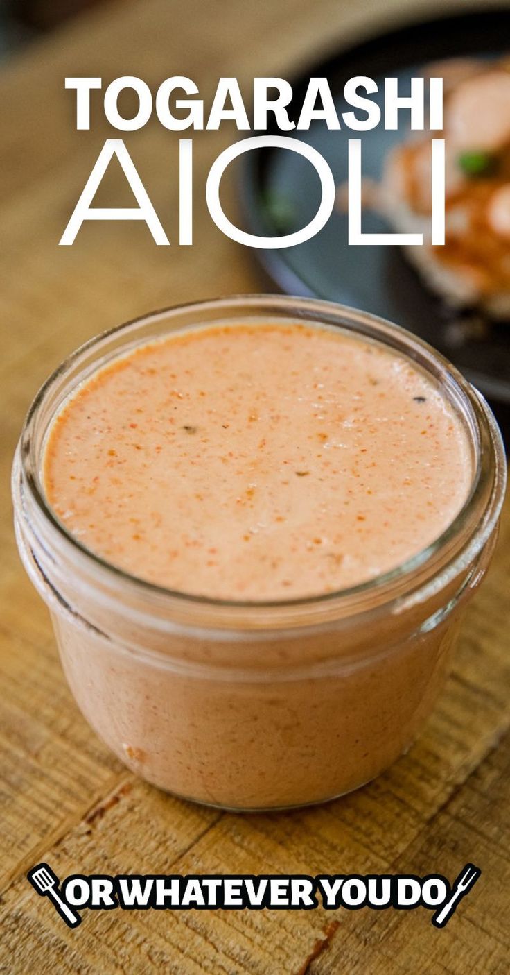 a glass jar filled with liquid sitting on top of a wooden table next to a plate of food