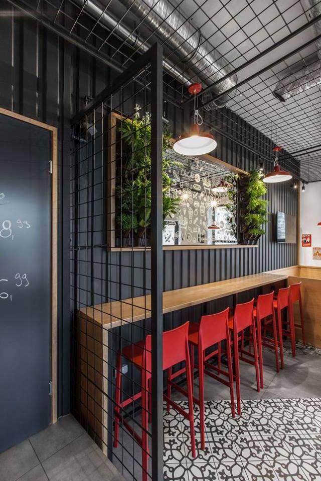 the interior of a restaurant with red chairs and black walls, along with a chalkboard on the wall