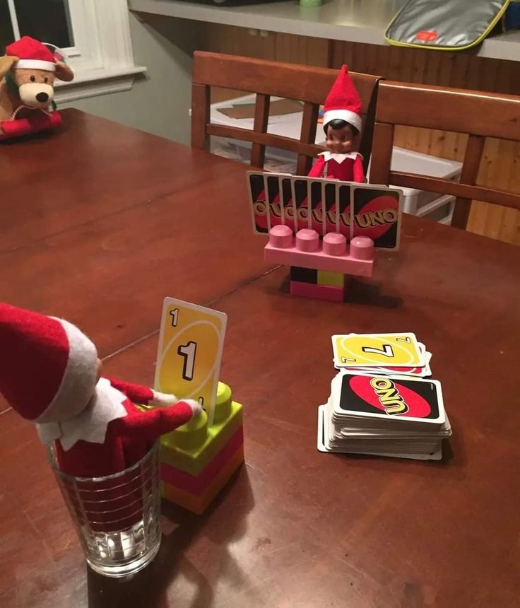 two elfs are sitting at a table with candy bars and other items on the table