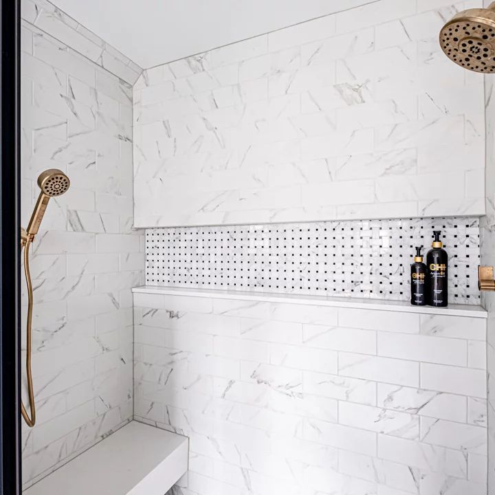 a bathroom with white marble walls and flooring, including a gold faucet