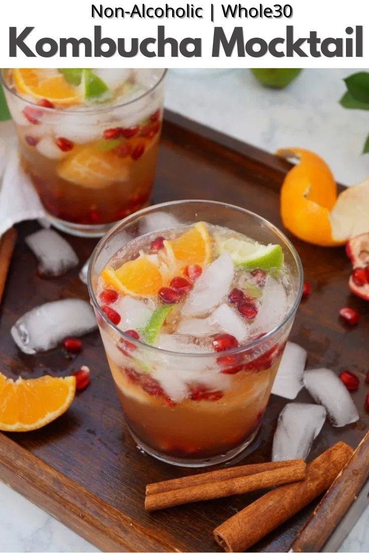 two glasses filled with drinks sitting on top of a wooden tray next to sliced oranges