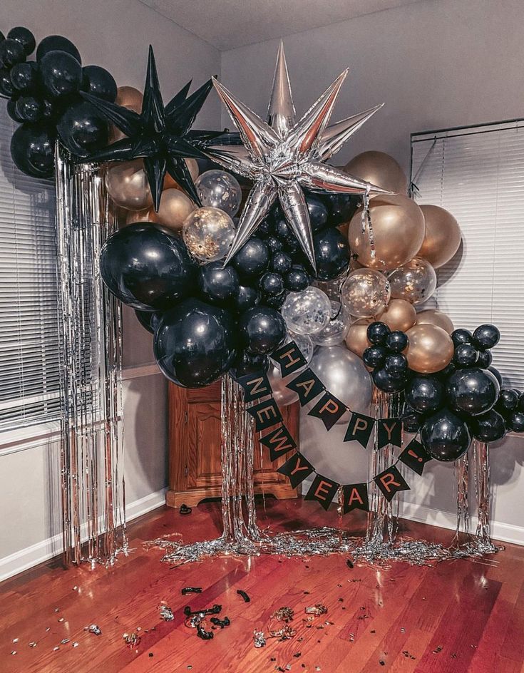 black and gold balloon arch with stars, balloons and streamers on the floor in front of it