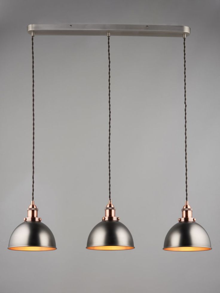 three pendant lights hanging from a metal bar with two black and one gold colored shades