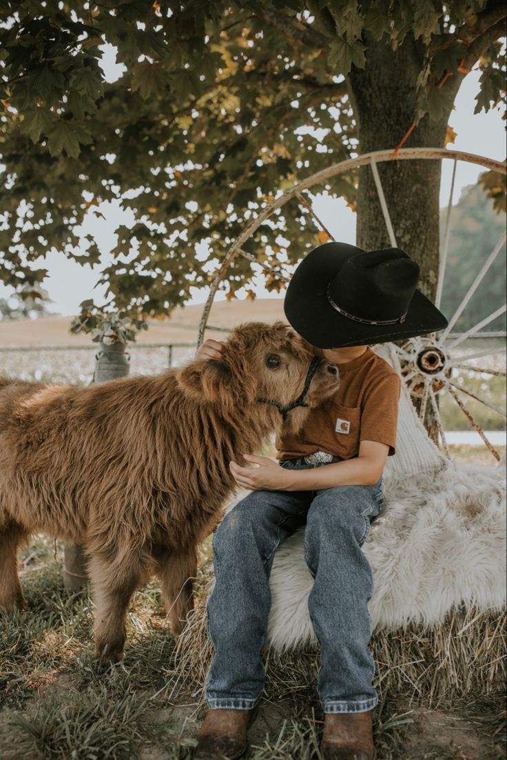 a man in cowboy hat sitting next to a brown dog with long hair on his head