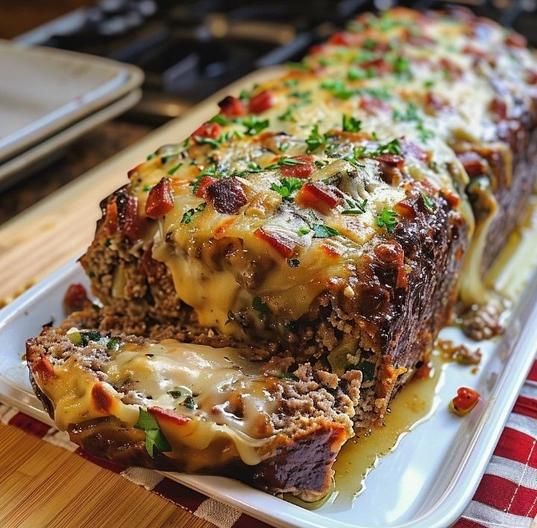 two slices of meatloaf on a white plate with cheese and green garnish