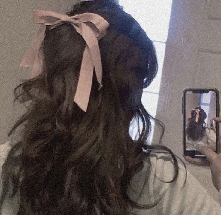 a woman is taking a selfie in the mirror with her hair tied up and wearing a pink bow