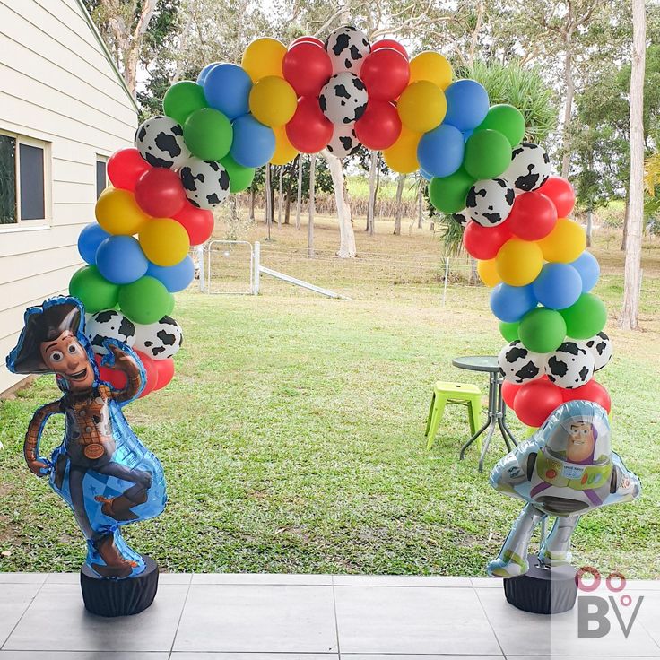 the balloon arch is decorated with soccer balls and other sports related items in front of a house