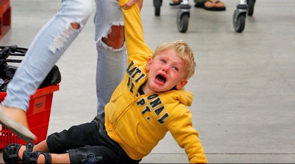 a young boy riding on top of a skateboard next to a woman in jeans