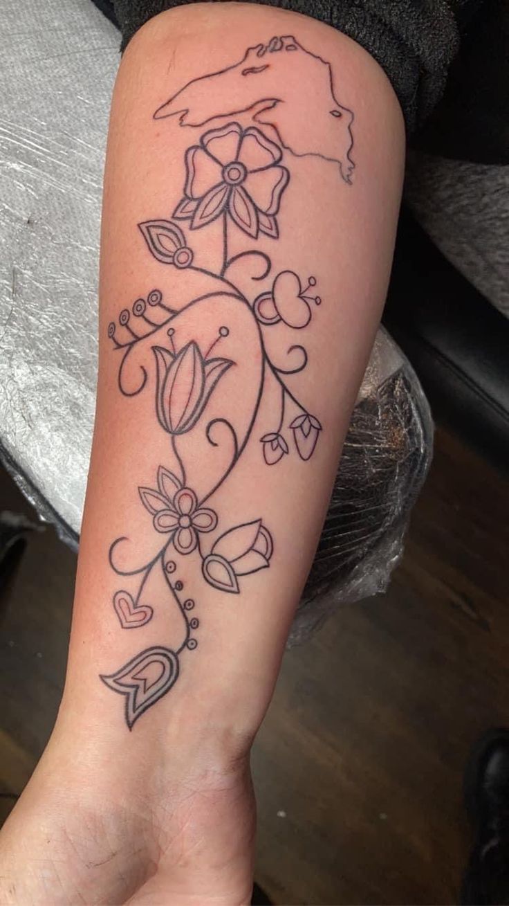 a woman's arm with tattoos on it and an image of a flower in the middle