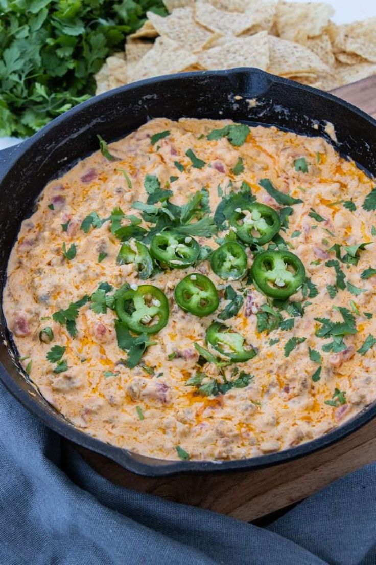 a black skillet filled with cheese and green peppers next to tortilla chips