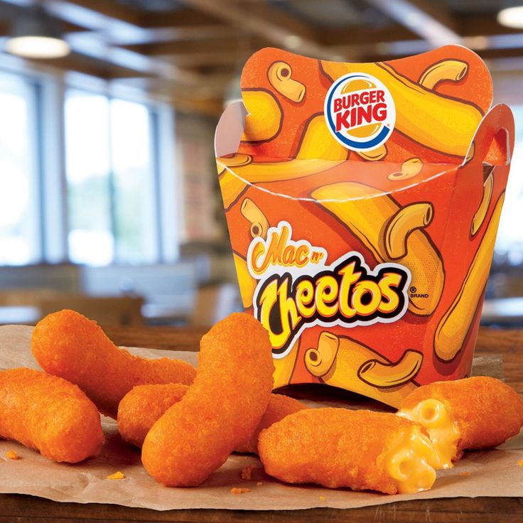 a box of cheetos sitting on top of a table next to some fried food