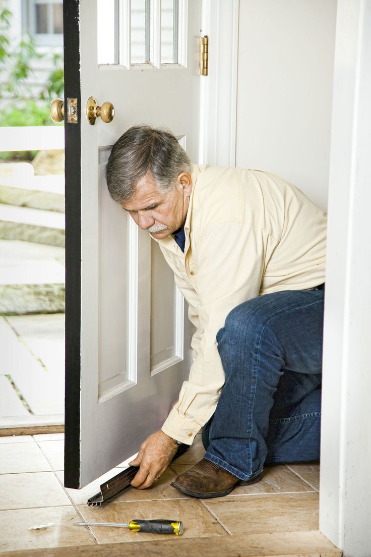 a man is opening the door with a drill and screwdriver in front of him