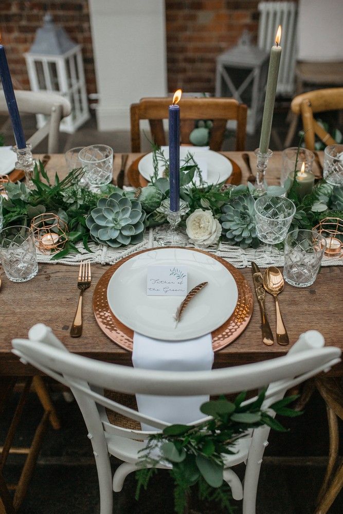 the table is set with white and gold plates, silverware, succulents and candles