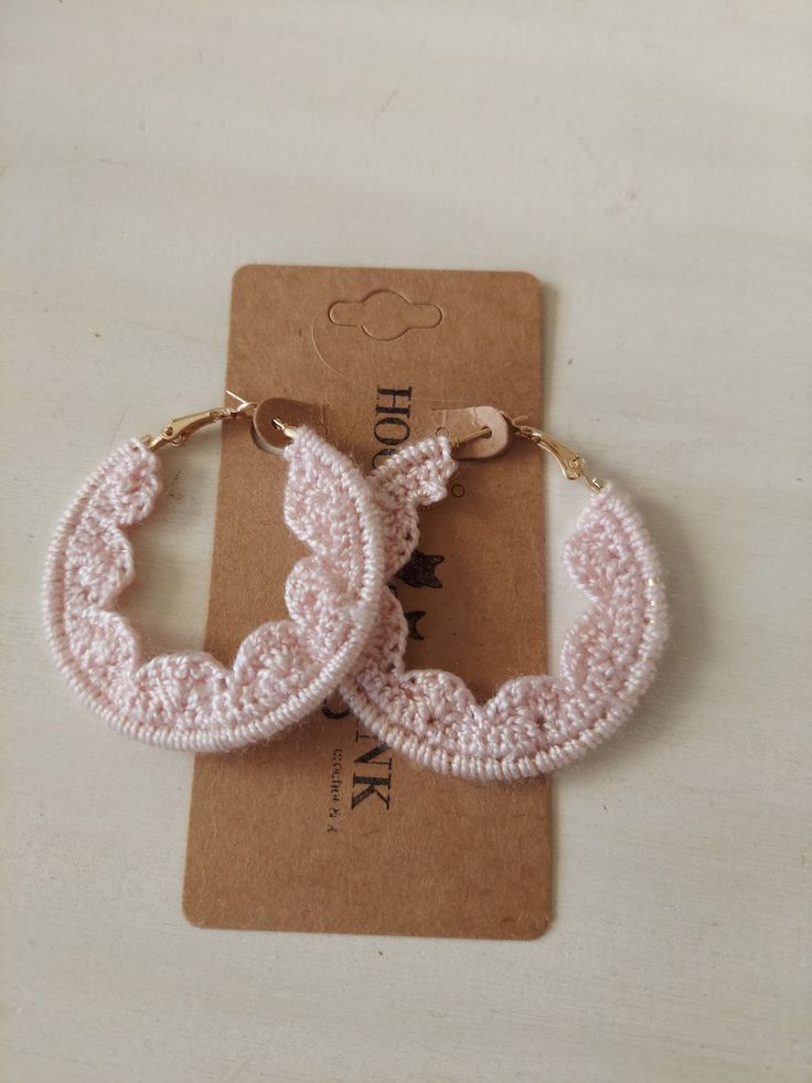 two pairs of pink crocheted hoop earrings sitting on top of a brown card