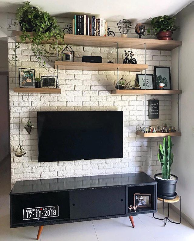 there is a tv on the wall in the room with shelves and plants around it