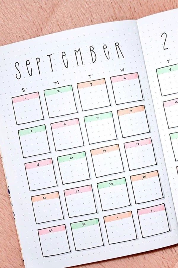 an open planner with the month on it and a pen next to it, sitting on top of a pink surface