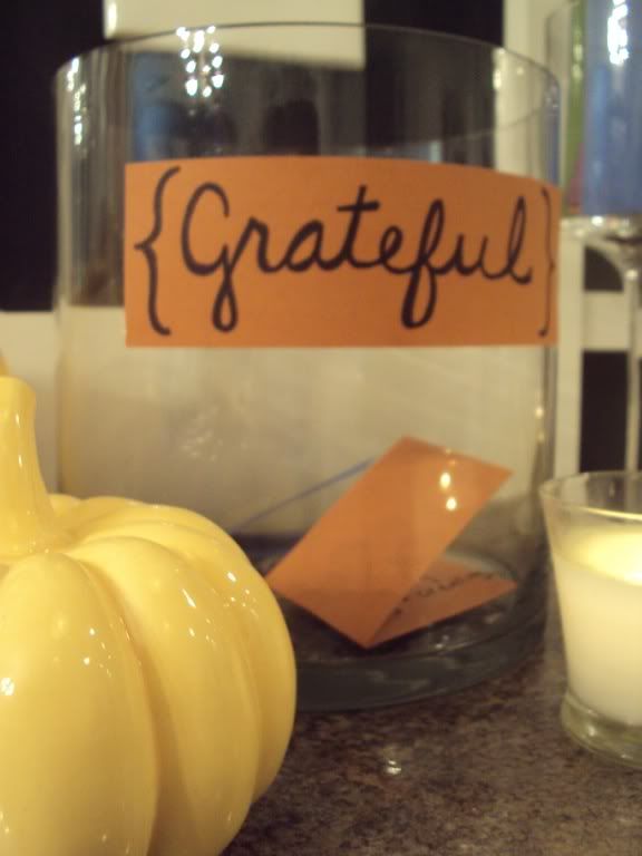 a candle and some pumpkins sitting on a counter with a sign that says grateful