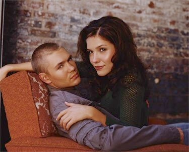 a young man and woman cuddle together in an old - fashioned chair, leaning on each other