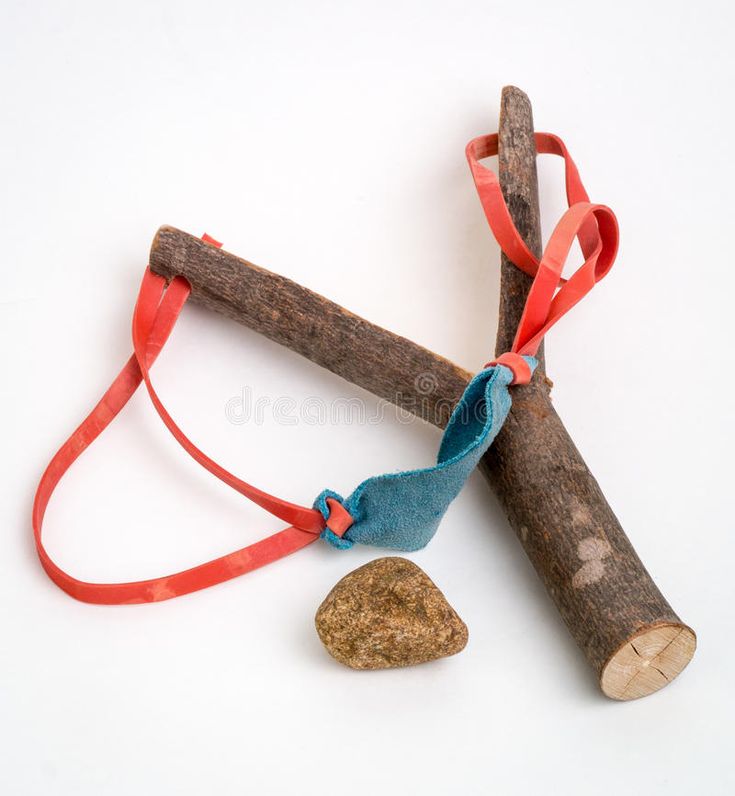 two sticks and a rock tied together on a white surface with red ribbon around them