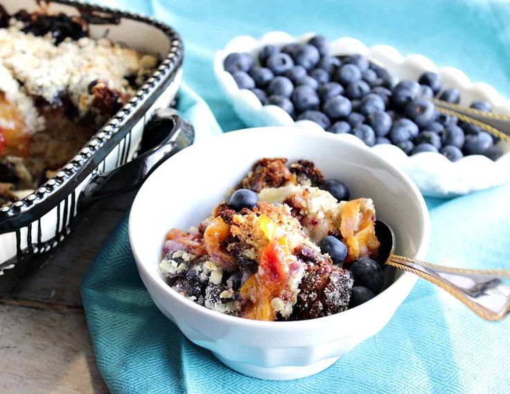 blueberry cobbler in a white bowl next to other desserts