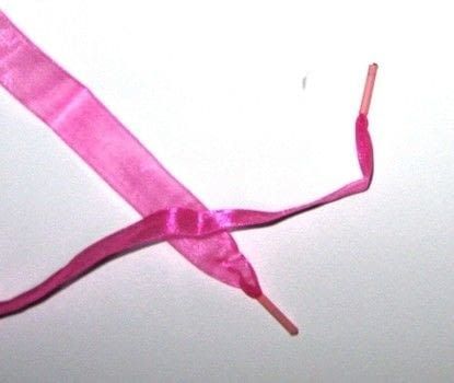 a pink ribbon with a single toothbrush sticking out of it's end on a white surface