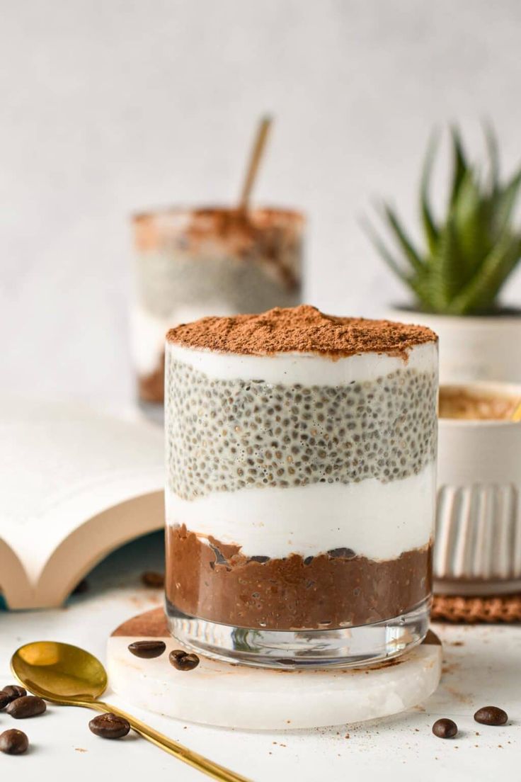 two desserts are sitting on a table with spoons and an open book in the background