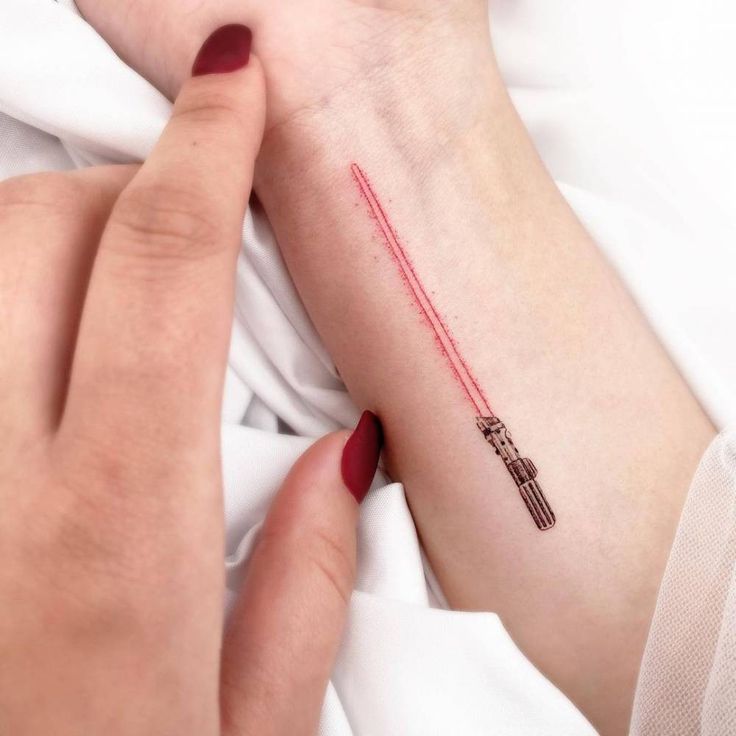 a woman's arm with a red light saber tattoo on it