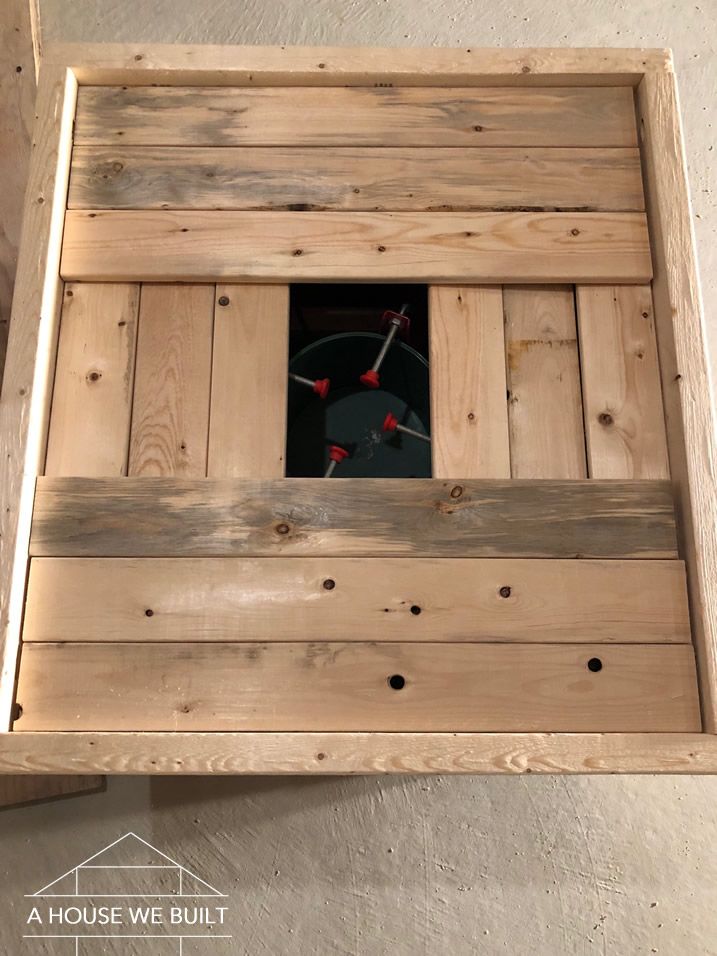 a wooden box with a clock in the center and holes in the bottom that are made to look like wood