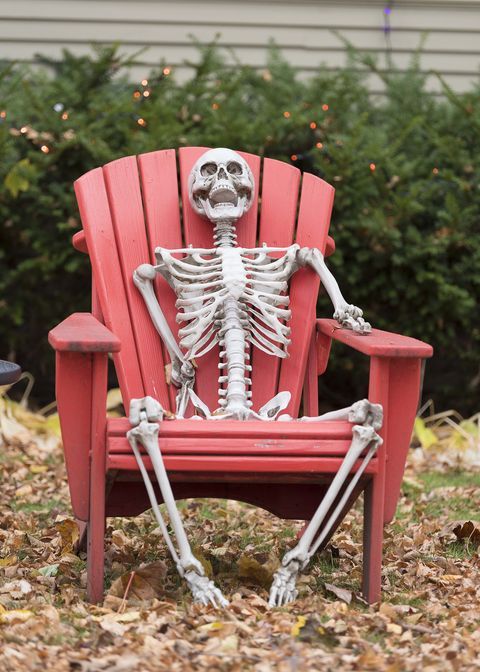 a skeleton sitting in a red lawn chair