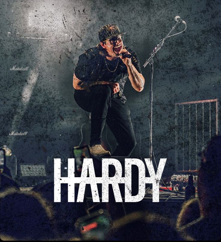 a man standing on top of a stage holding a microphone in front of him with the words hardy written across it