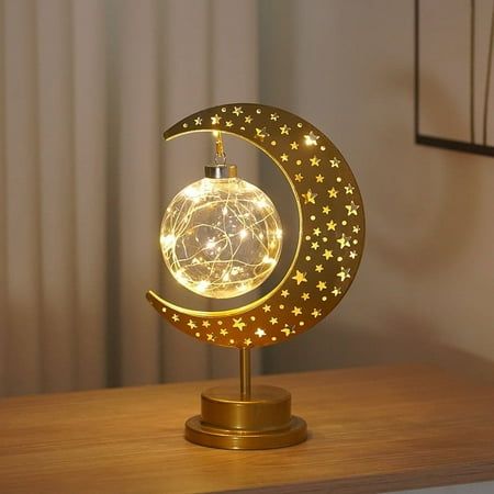 an illuminated moon and star decoration on a wooden table