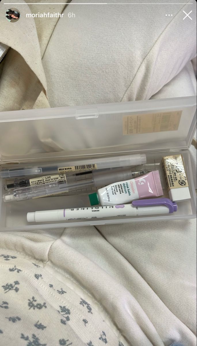 an open plastic box containing three different types of toothbrushes and one tube of eyeliner