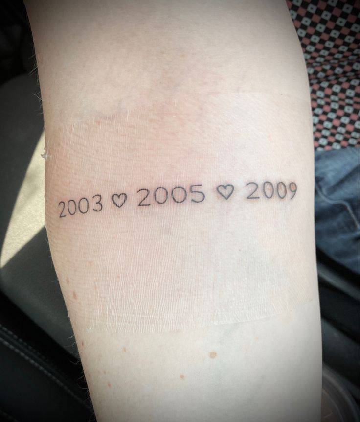 a person with a tattoo on their arm that reads, 2003 - 2009 and hearts