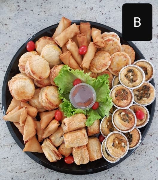 a black plate topped with lots of food next to small bowls filled with dipping sauce