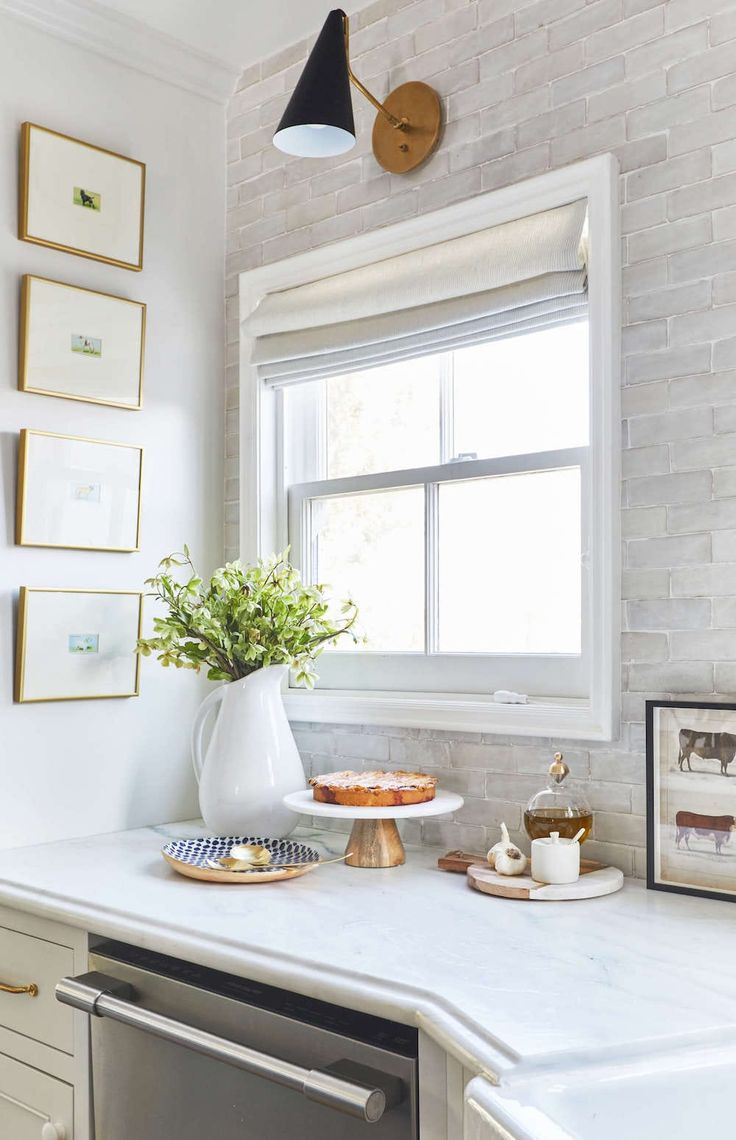 a kitchen with white counter tops and gold trim on the window sill is shown