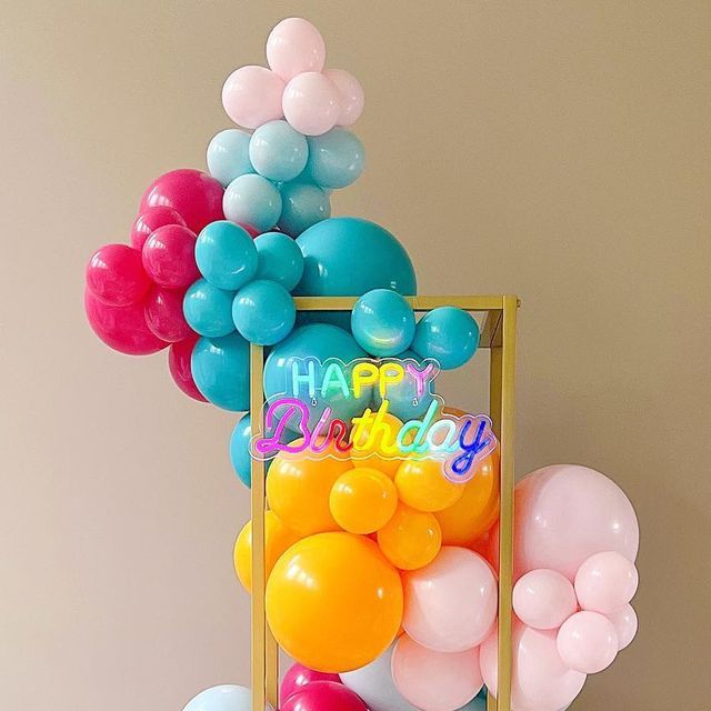 there is a birthday cake with balloons on the table and a sign that says happy birthday