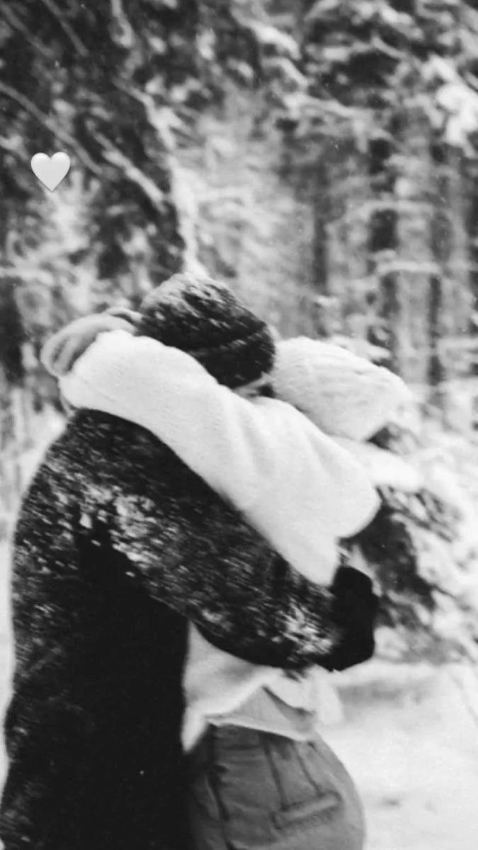 black and white photograph of two people walking in the snow with a heart on their back