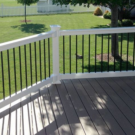 a white deck with black rails and a bird on the grass in front of it