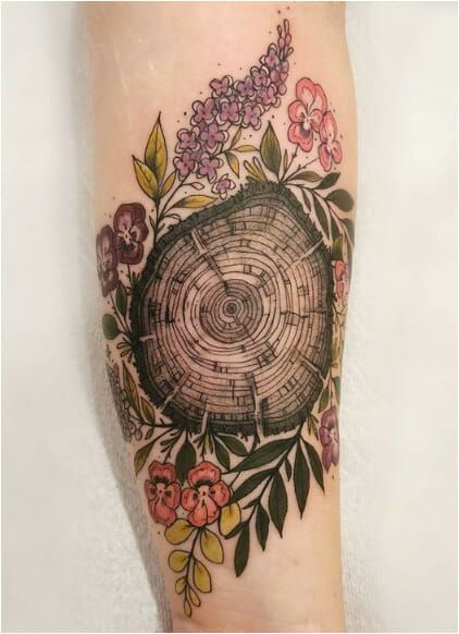 a tree stump with flowers around it on the right forearm and leg tattoo design by person