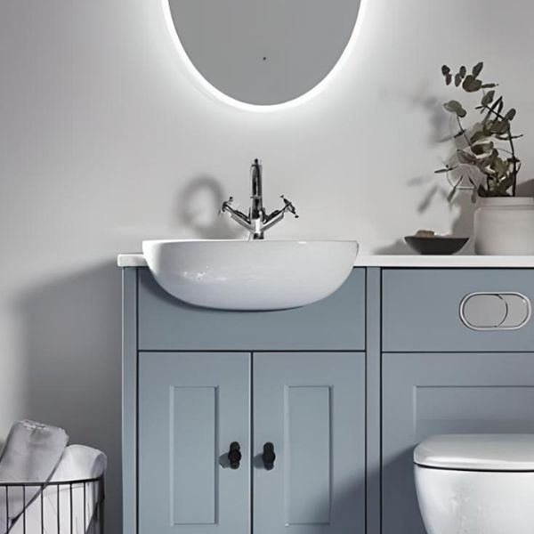 a white toilet sitting next to a bathroom sink under a round mirror on a wall