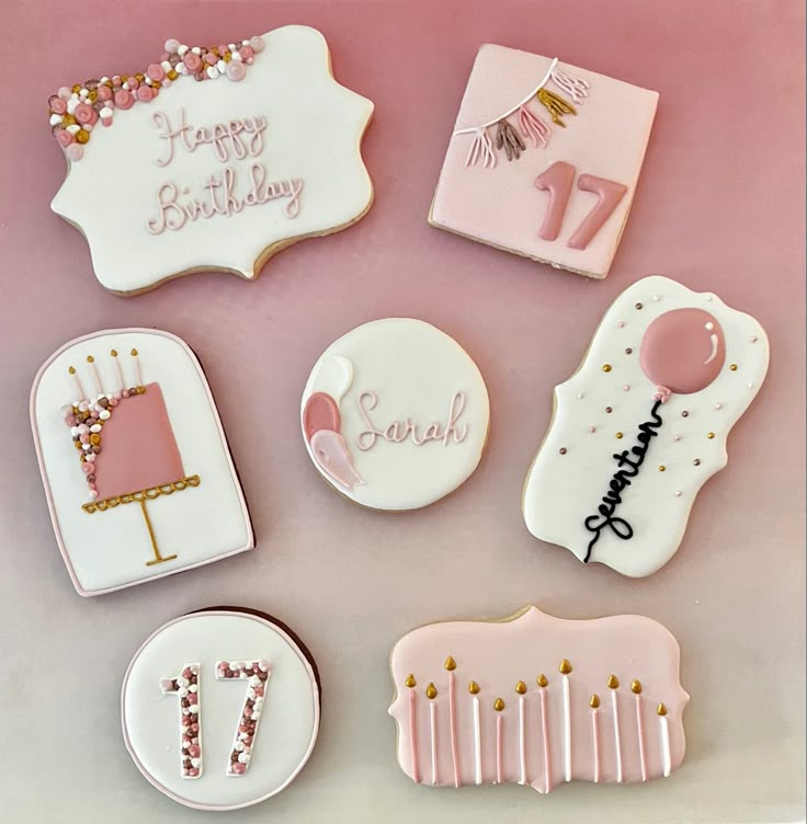 decorated cookies with pink icing and white frosting are arranged in the shape of birthday cakes