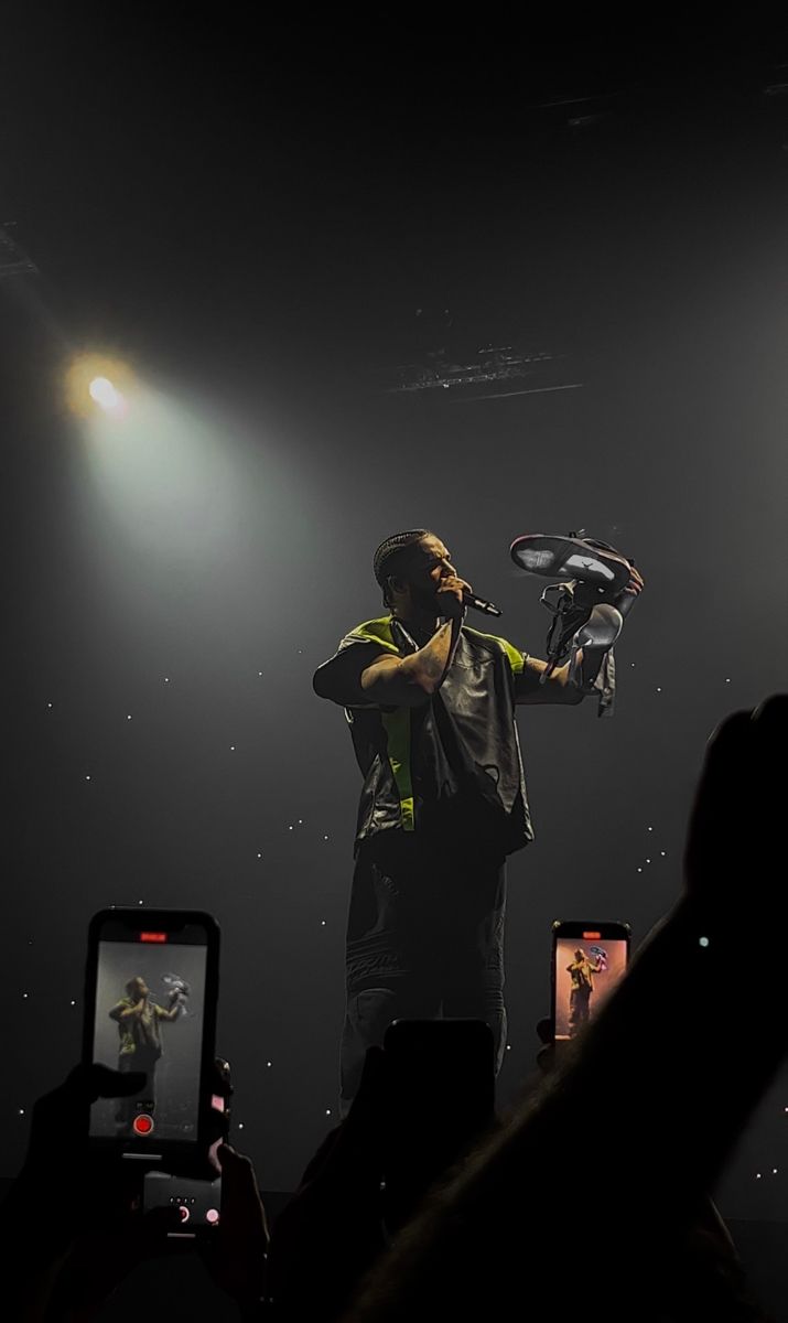 a man standing on top of a stage holding a cell phone