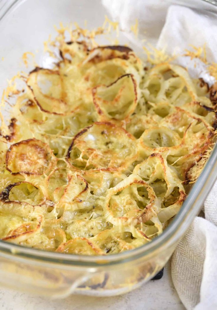 a casserole dish with cheese and other toppings in a glass baking dish