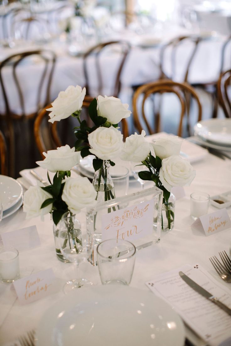 the table is set with white flowers and place cards