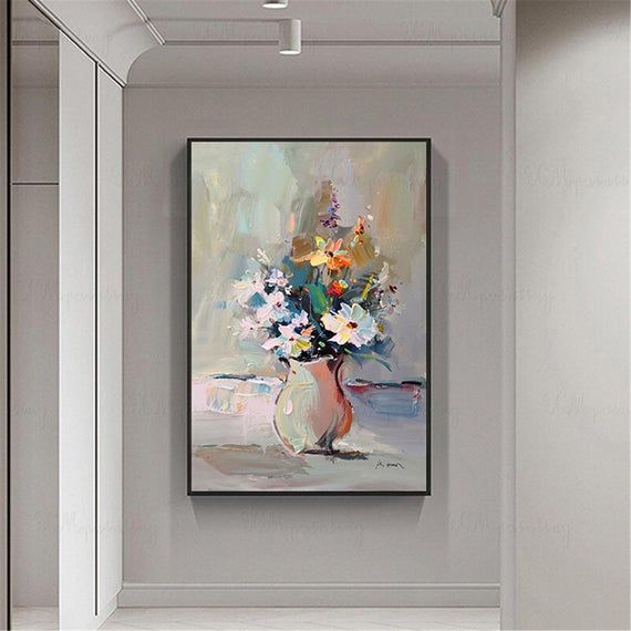 a painting hanging on the wall next to a vase with flowers in it and an open door