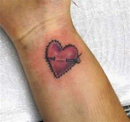 a small heart tattoo on the wrist