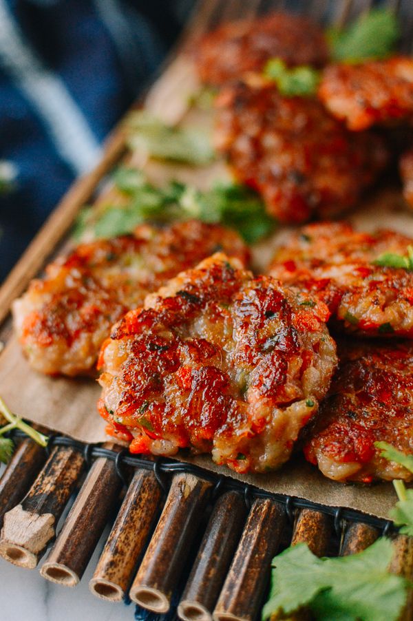 some meat patties are sitting on a cutting board next to cilantro and parsley