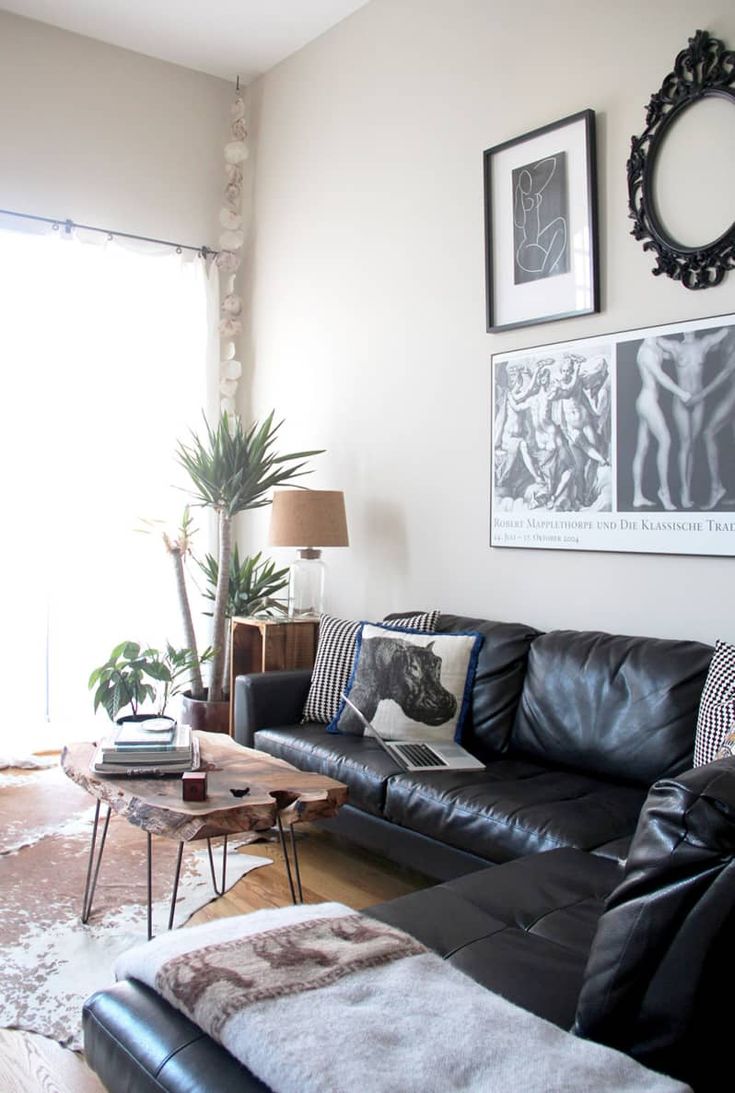 a living room with black leather couches and pictures on the wall