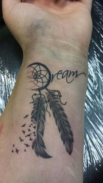 a woman's wrist with a dream catcher tattoo on it and the words dream written in cursive writing